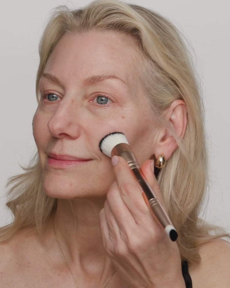 Rijpere vrouw blendt Changing Foundation met een 2-in-1 Build & Conceal Brush voor een natuurlijke finish.