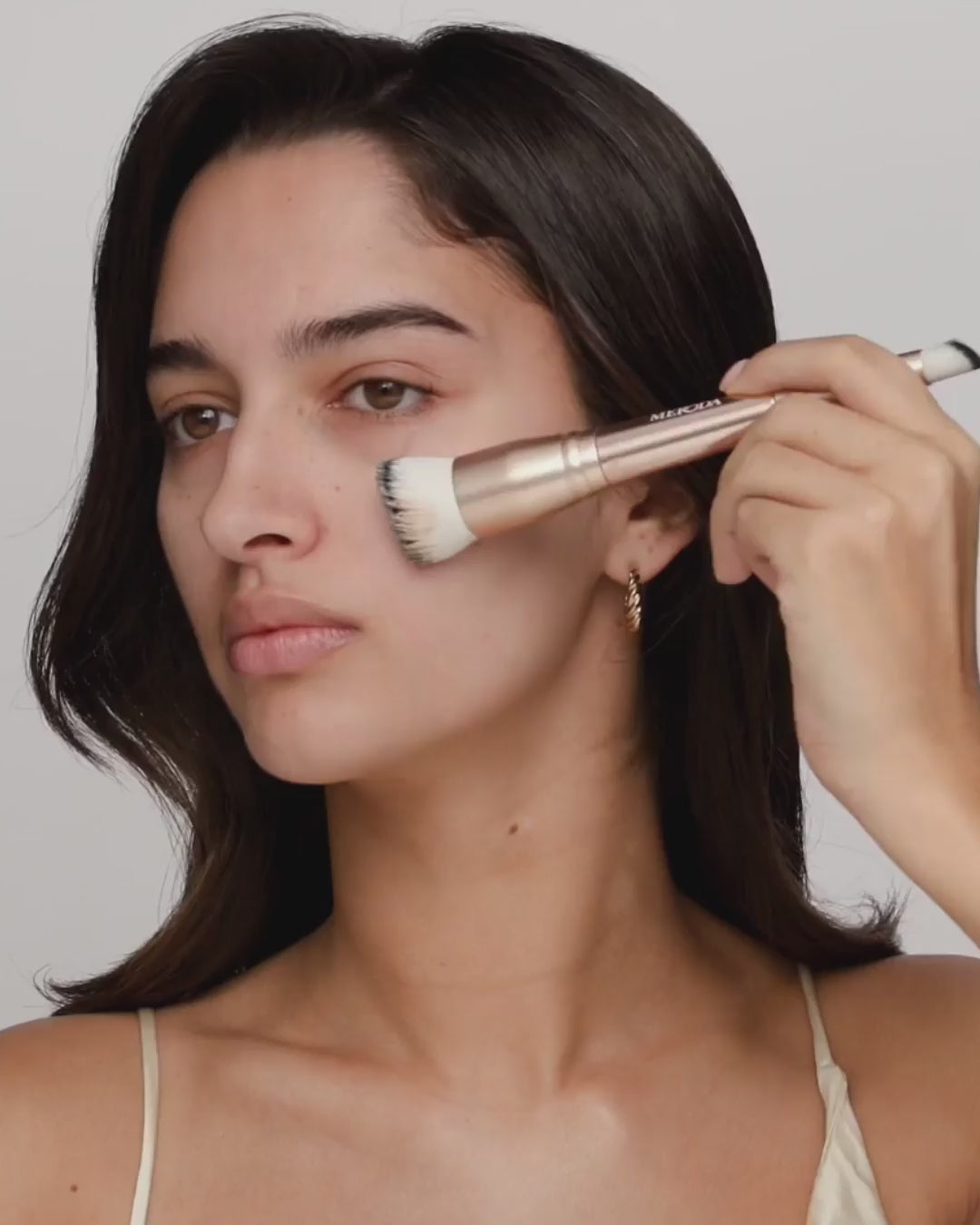 Model brengt Changing Foundation aan met de 2-in-1 Build and Conceal Brush voor een egale teint.
