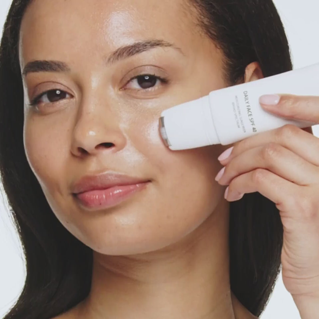 Vrouw brengt Daily Face SPF 40 aan met de metalen rollerball voor een gehydrateerde, stralende teint.