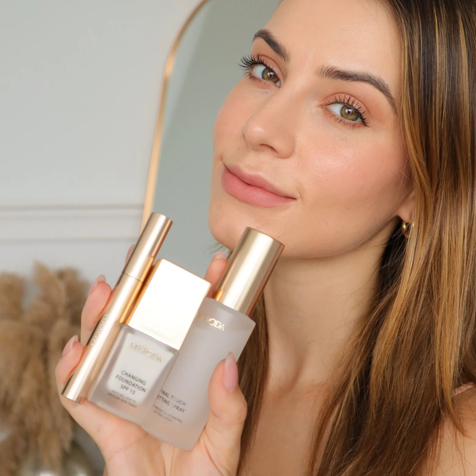 Travel Kit met mini Changing Foundation, Final Touch Setting Spray en Gilded Lashes Mascara vastgehouden door een model.