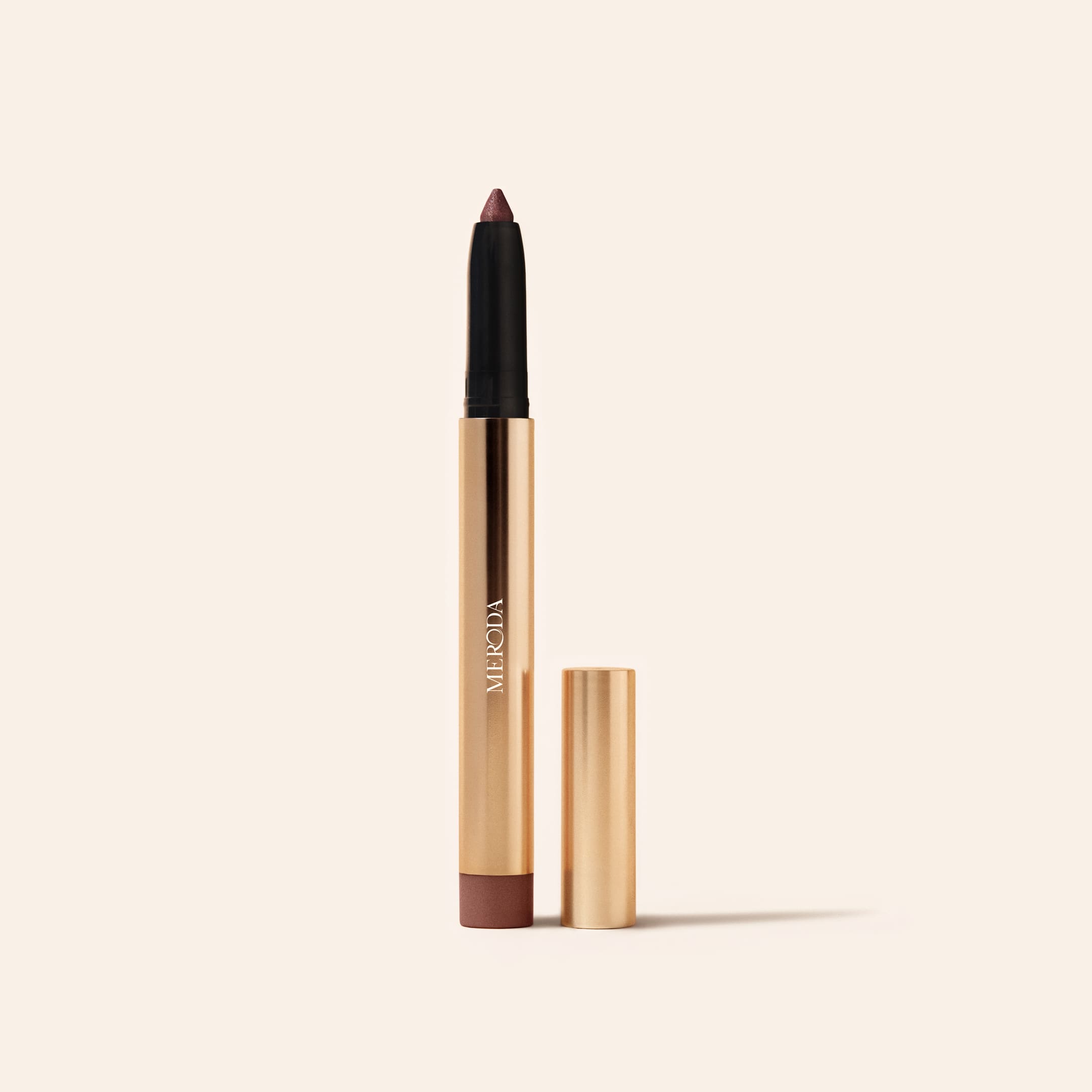 Meroda Eye Perfecting Shimmer Stick in Mauve, geopend in een gouden huls op een lichte achtergrond.