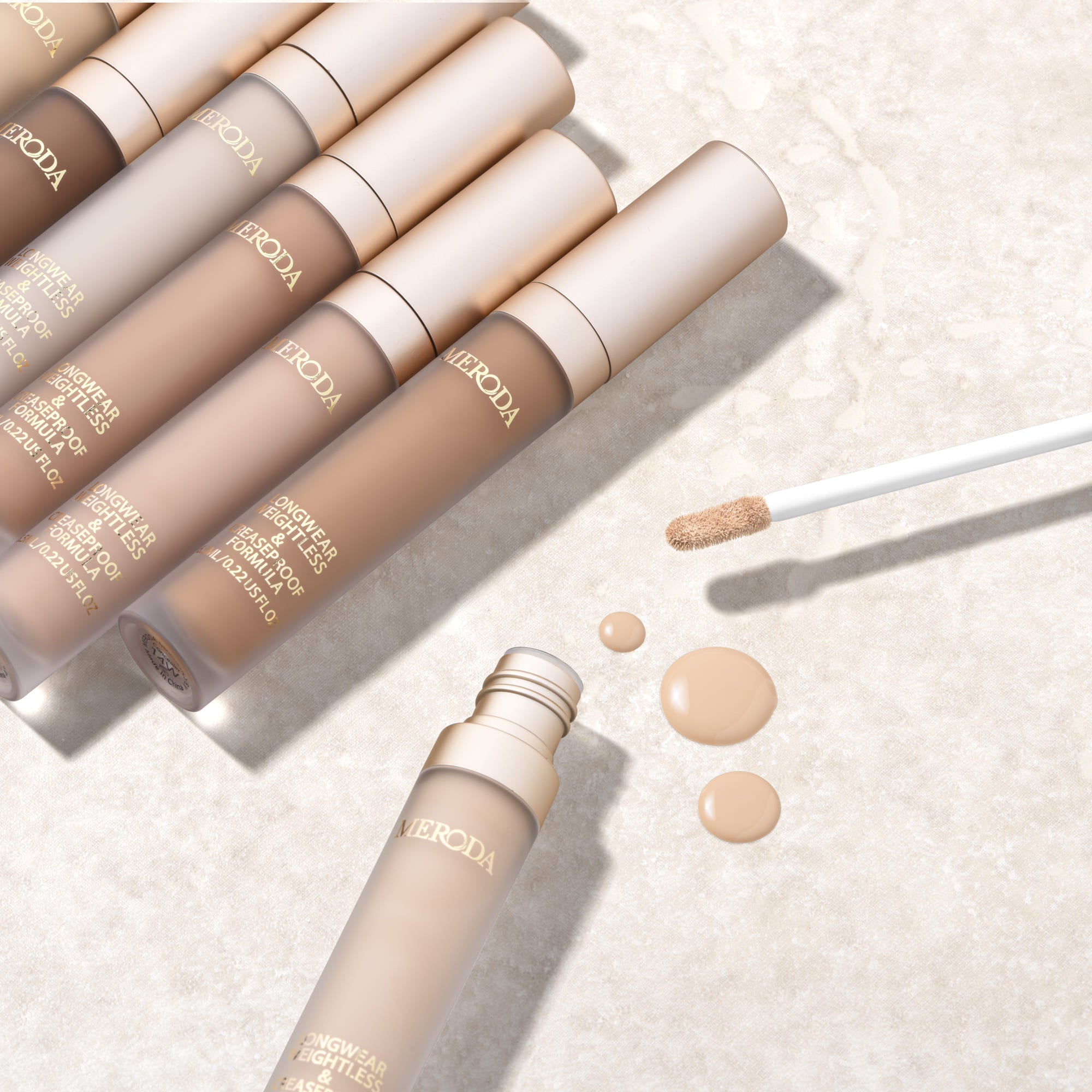 Universal Concealer in diverse tinten met een romige vloeibare textuur en applicator op een stenen achtergrond