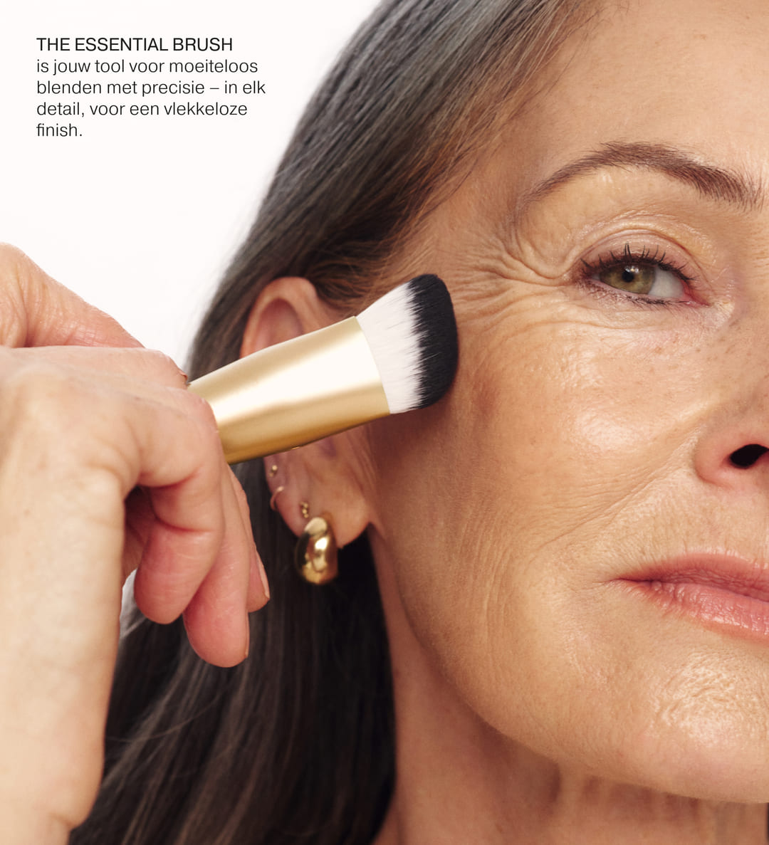 The Essential Brush met gouden handvat op een rijpere huid voor moeiteloos blenden en een vlekkeloze finish