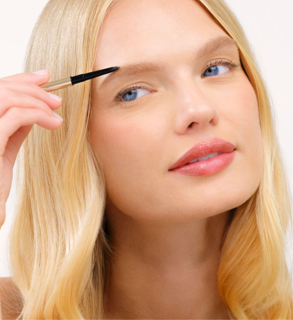 Hydrating Lip Tint op een blond model dat een wenkbrauwpotlood aanbrengt voor een natuurlijke look