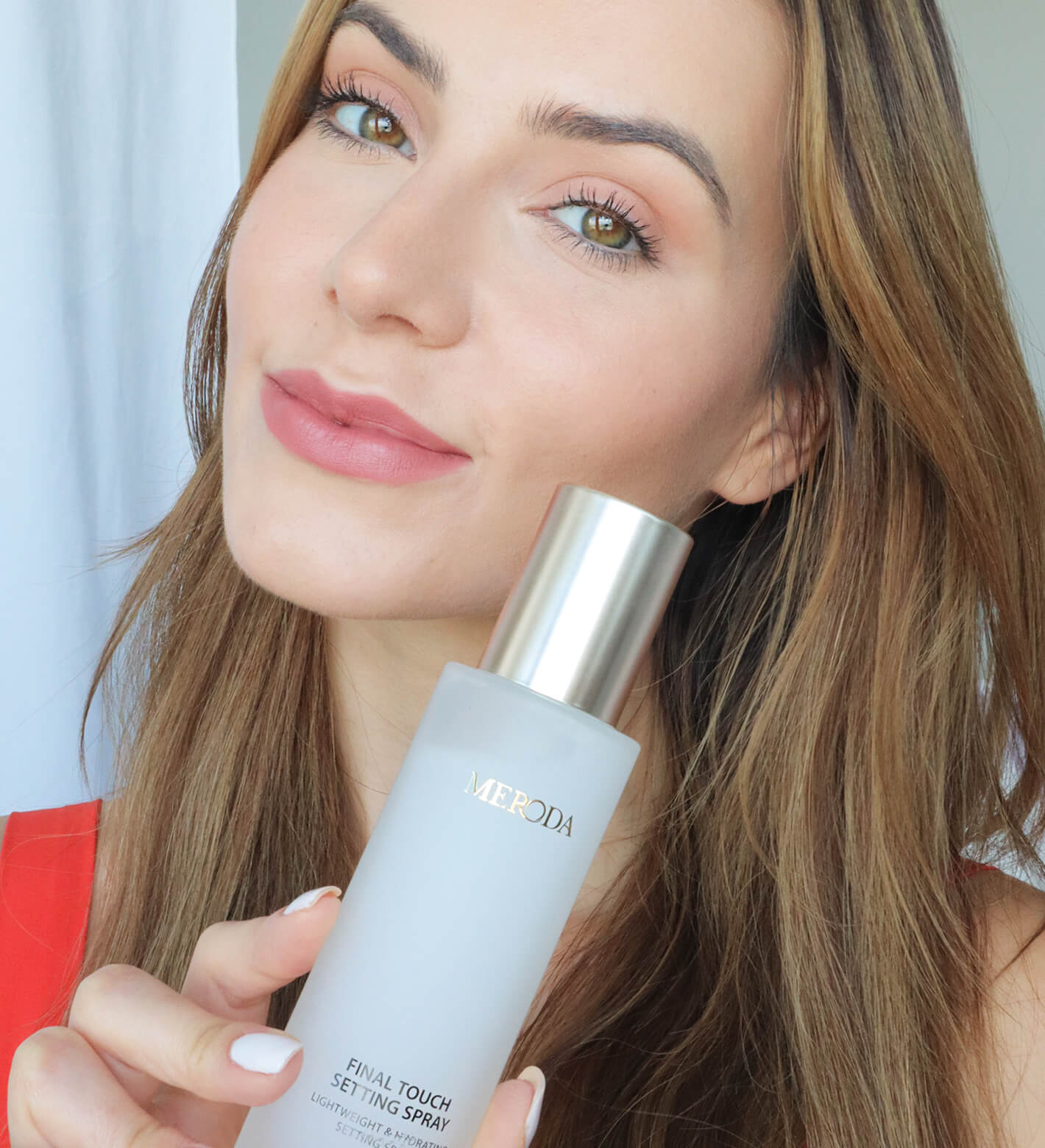 Final Touch Setting Spray vastgehouden door een model met natuurlijke make-up en een stralende huid
