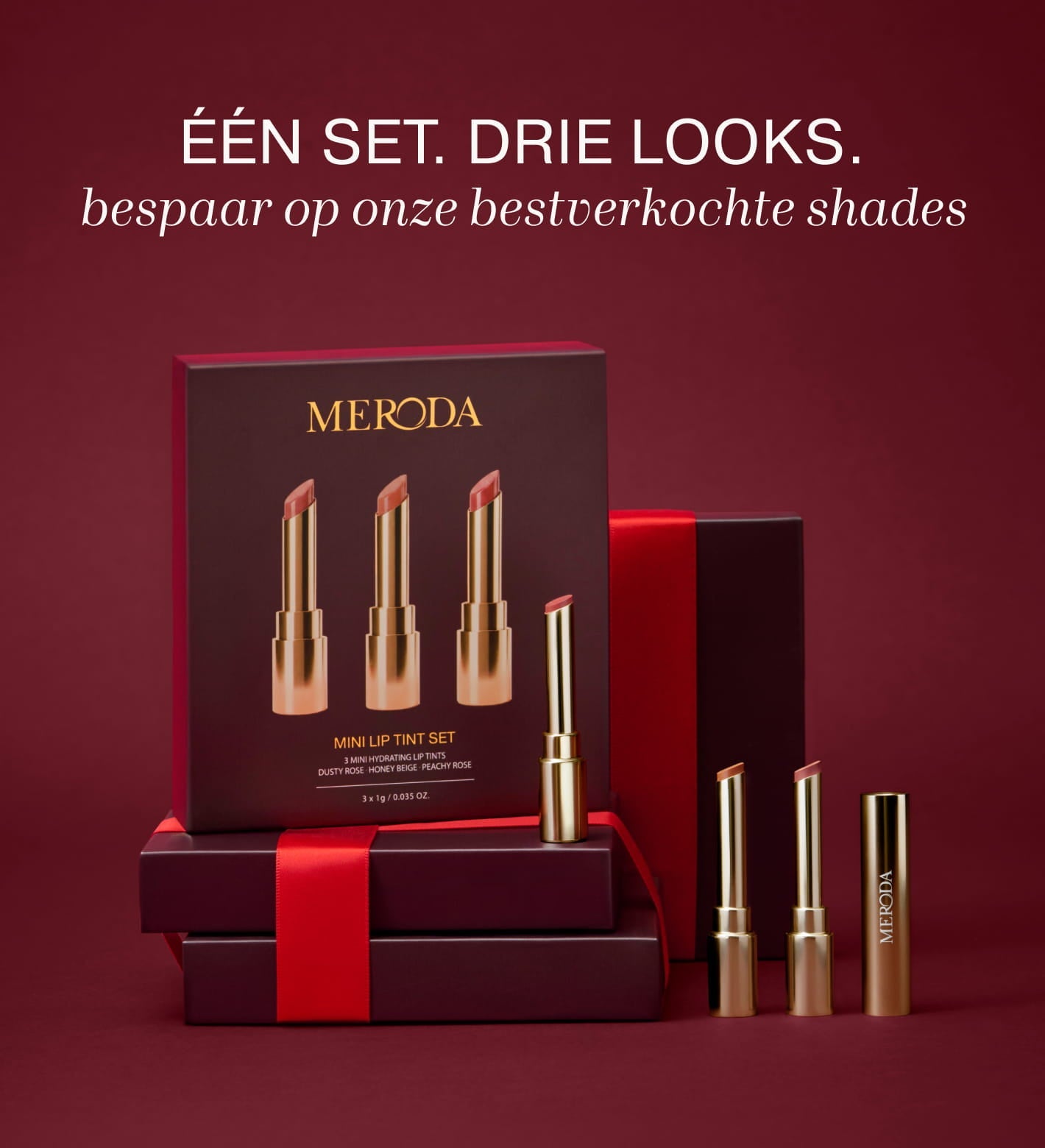Mini Lip Tint Trio met drie hydraterende tinten in elegante gouden verpakking op een bordeauxrode achtergrond.