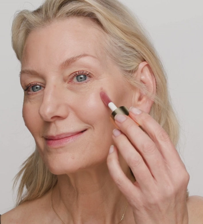 Rijpere vrouw blendt de Vibrant Cheek Blush in Dusty Rose met een make-upkwast voor een natuurlijke gloed.